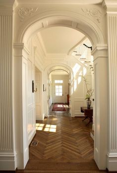 an archway leading to a hallway with wood floors and white walls, along with wooden parquet flooring