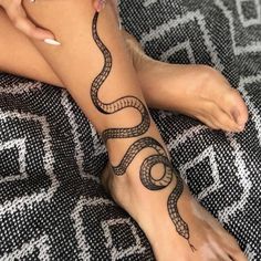 a woman's foot with a snake tattoo on it