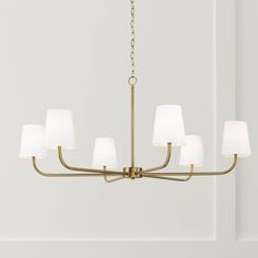 a brass chandelier with six white shades on the top and bottom, hanging from a chain