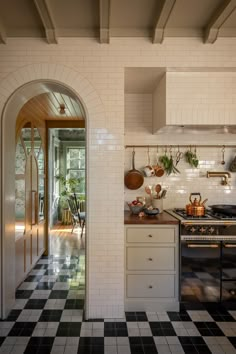 a kitchen with black and white checkered flooring, an arched doorway leading to the dining room