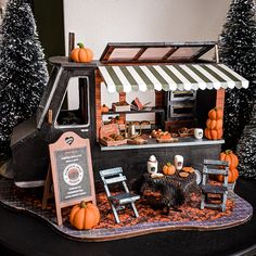 a miniature model of a food truck with pumpkins on the outside and an awning