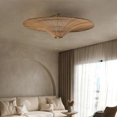 a living room filled with furniture and a round light fixture hanging from the ceiling above