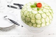 a cake with cucumbers and leaves on it sitting on a table next to silverware