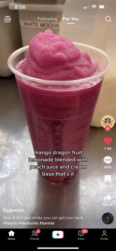 a pink drink in a plastic cup sitting on top of a table