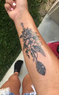 a woman's arm with flowers and feathers on it