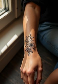 a woman's arm with a flower tattoo on her left wrist and right hand