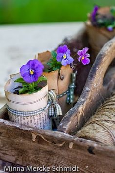 some purple flowers are in a pot on a wooden stand with other things around it