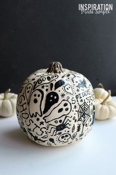 a black and white painted pumpkin sitting on top of a table next to small white pumpkins