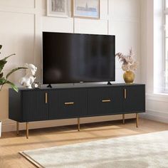 a large flat screen tv sitting on top of a wooden entertainment center next to a potted plant