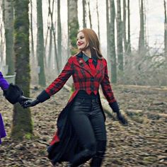 two women are walking through the woods holding each other's hands while wearing black gloves