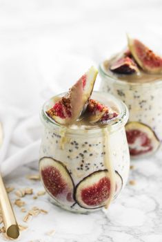 two jars filled with fruit and oatmeal on top of a white table