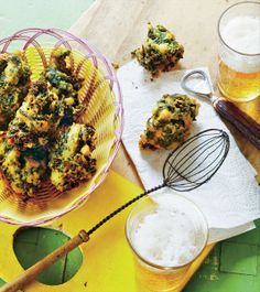 a table topped with lots of food next to two mugs filled with beer and whisks