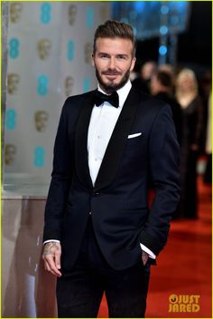 a man in a tuxedo standing on a red carpet