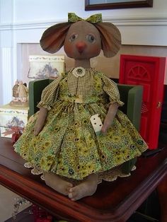 a stuffed animal wearing a dress and holding a dice on top of a wooden table