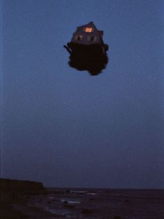 an upside down house on the beach at night with water reflecting off it's roof