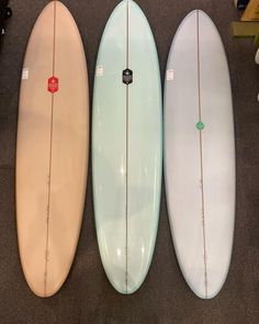 three surfboards are lined up on the floor next to each other in a row