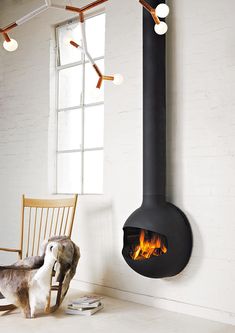 a dog standing next to a fire place in a room with a chair and window