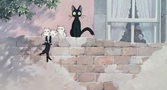 two black cats standing on the side of a brick wall next to a tree and window