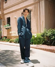 a man in a blue suit standing on the sidewalk