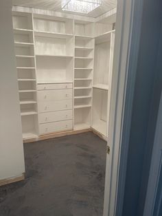 an empty walk in closet with white shelving