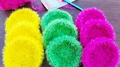 three pairs of fuzzy slippers next to a pair of knitting needles on a table