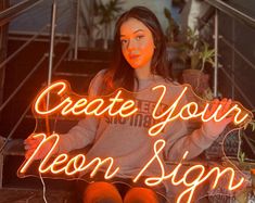 a woman sitting on the steps holding up a neon sign that says create your moon sign