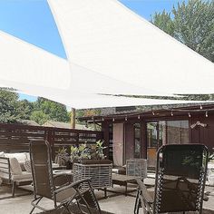 there are chairs and tables on the patio with an awning over them for shade