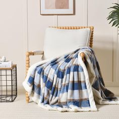 a blue and white blanket sitting on top of a chair next to a potted plant