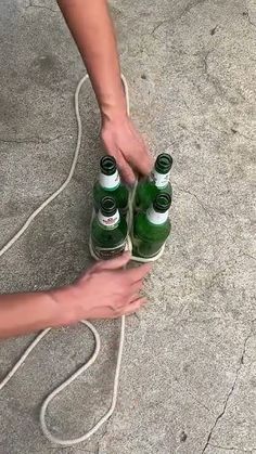 a person is holding two green bottles in their hand while another holds the other one