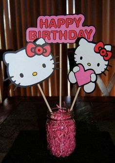 two hello kitty cupcake toppers in a mason jar with pink straws on the table