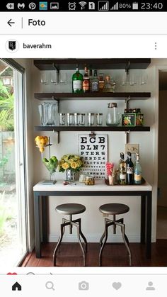 two stools in front of a bar with glasses and bottles on the top shelf