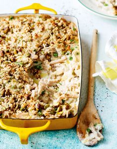 a casserole dish with chicken and rice in it next to a wooden spoon