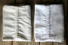 two pairs of white linens sitting on top of a wooden table next to each other