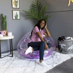 a woman sitting on top of a bubble chair in front of a potted plant