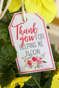 a thank you for helping me bloom tag hanging from a plant