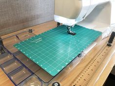 there is a sewing machine on top of a cutting mat that has been cut into pieces