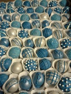 a box filled with blue and white chocolates on top of a table next to other candies