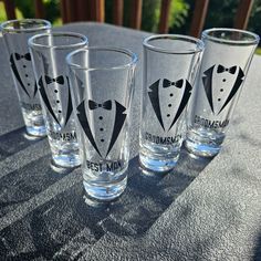 four shot glasses with tuxedos on them sitting on a table