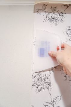 a person is holding a piece of paper and pressing it on the wall