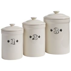 three white canisters with black numbers and clover designs on them, one is empty