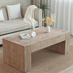 a living room with a couch, coffee table and flowers in a vase on the floor