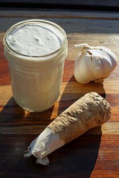 garlic and mayonnaise sitting on a cutting board next to a jar of dressing