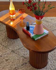 a wooden table with two vases on top of it and flowers in the middle