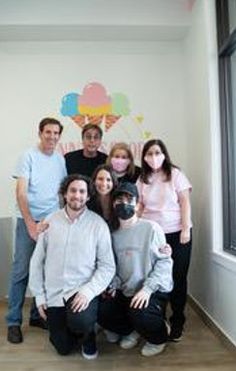 a group of people standing next to each other in front of a wall with balloons on it