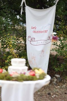 a cake sitting on top of a white plate next to a banner that says let's celebrate