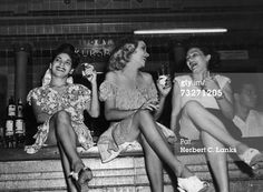 three women sitting at a bar laughing and drinking