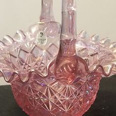 a pink glass vase with two wine bottles in the shape of hearts on it's sides