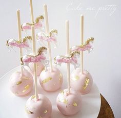 cake pops with pink and gold decorations on a white platter, ready to be eaten