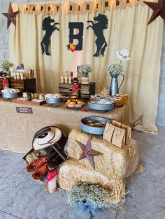 a birthday party with hay bales, decorations and desserts on the table in front of a curtain