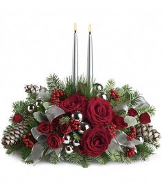 christmas centerpiece with red roses and pine cones, silver candlesticks and holly berries